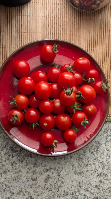 Ein roter Teller mit einer Vielzahl von kleinen, frischen Tomaten.