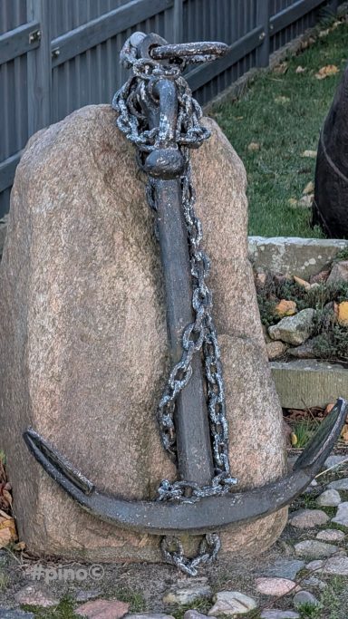 Eisenanker mit Kette, auf einem runden, grauen Stein platziert.