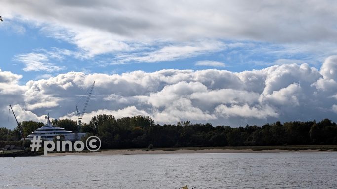 Silhouette eines Ufers mit Wolken und einem Kühlturm im Hintergrund.