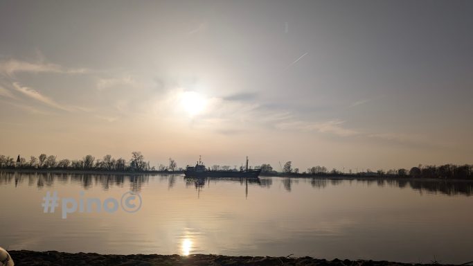 Sonnenaufgang über einem ruhigen See mit Spiegelungen der Bäume am Ufer.
