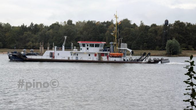 Ein Schaufelboot fährt auf einem ruhigen Fluss mit grünen Ufern im Hintergrund.