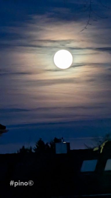 Helle Vollmondnacht hinter einer bewölkten Skyline.