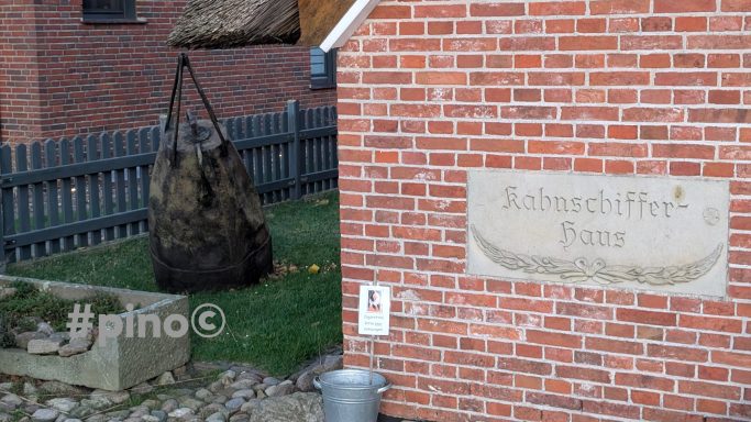 Grau und braun gefleckter Sack aus Stroh neben einem roten Backsteingebäude.