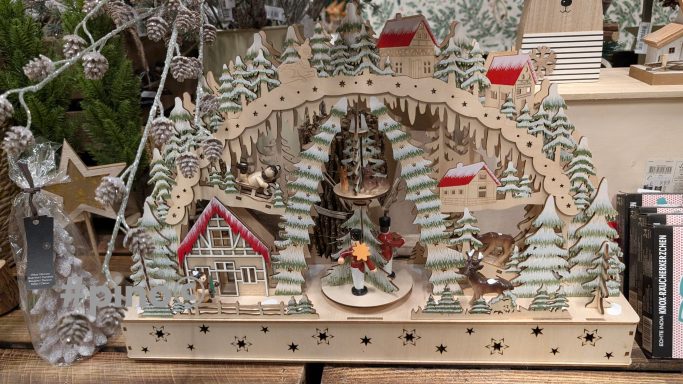 Weihnachtliche Holzspielzeuglandschaft mit Tannenbäumen, Häusern und Figuren.