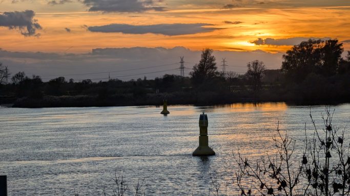 Sonnenuntergang über einem ruhigen Gewässer mit gelben Markierungsbojen.