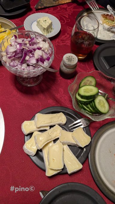 Ein Tisch mit Käse, Zwiebeln, Gurken und einer Schüssel mit Salat.