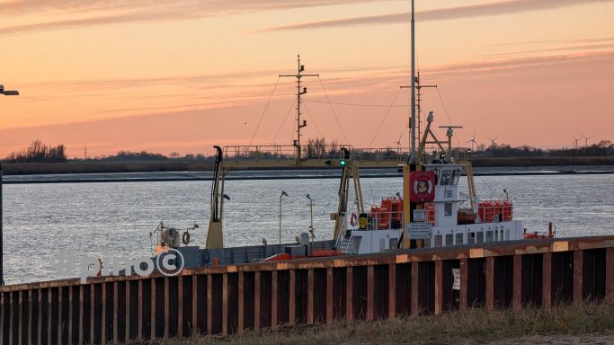 Ein Schiff liegt an einem Pier, umgeben von einem Sonnenuntergang im Hintergrund.