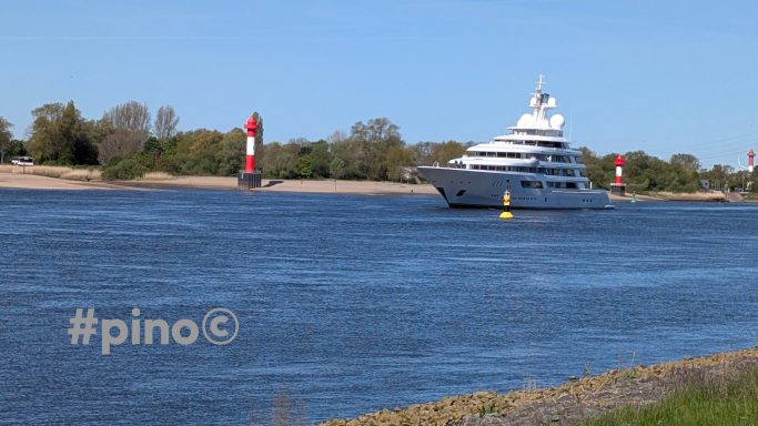 Luxusyacht fährt auf ruhigem Wasser vorbei an markierten Hafenleuchttürmen.