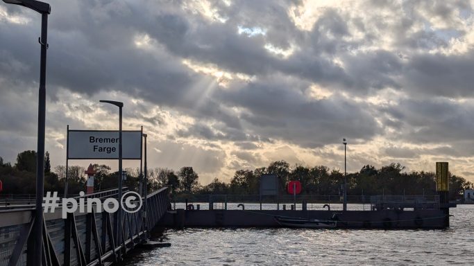 Schiffsanleger mit Wolken und Sonnenstrahlen über dem Wasser.