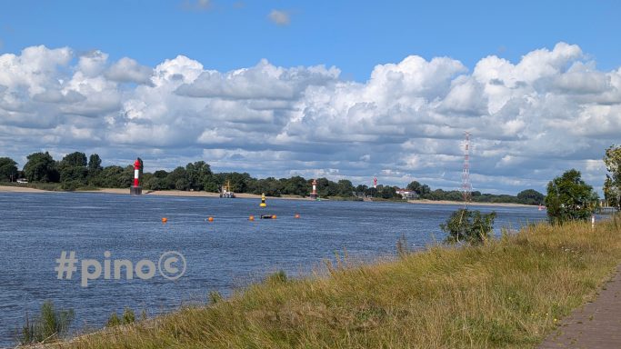 Blick auf einen Fluss mit segelnden Booten und einer bewölkten Himmel über dem Ufer.