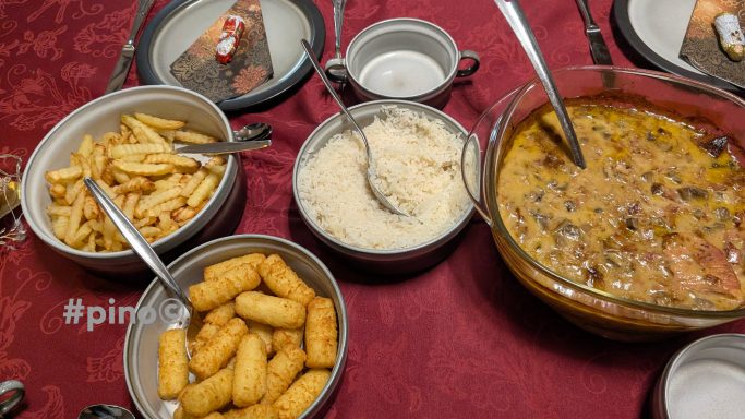 Ein Tisch mit verschiedenen Gerichten: Pommes, Reis, Soße und Gebäck.