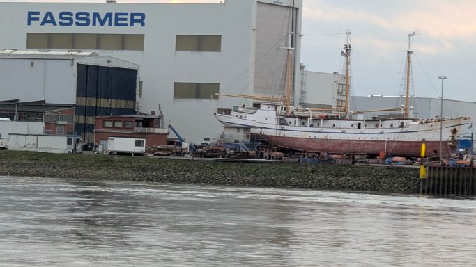 Fassmer-Werft mit Schiff im Dock und Wasser im Vordergrund.