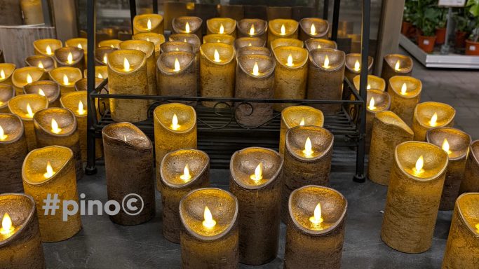 Beleuchtete, rustikale Kerzen in verschiedenen Höhen auf einem Tisch arranged.