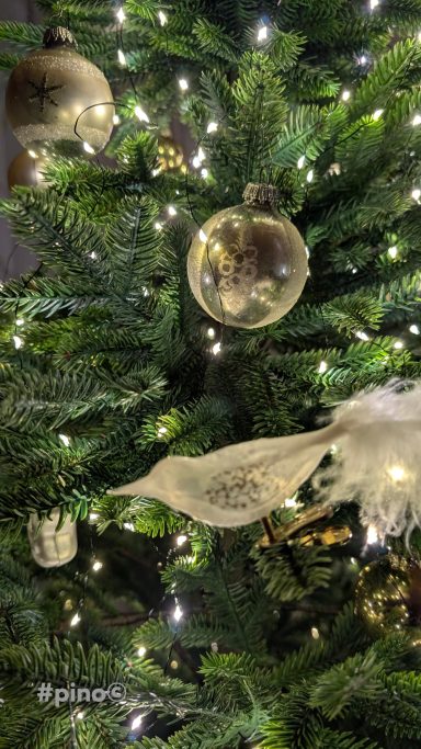 Weihnachtsbaum mit Glaskugeln, Schneeflocken und warmem Licht.