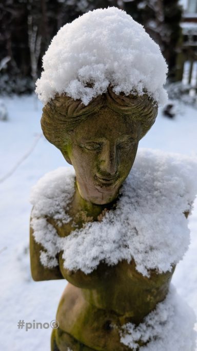 Eine Statue mit schneebedecktem Kopf und Schultern in einer verschneiten Umgebung.