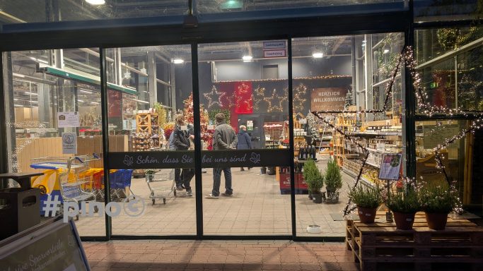 Ein Supermarkt mit Regalen voller Lebensmittel und Kunden beim Einkaufen.