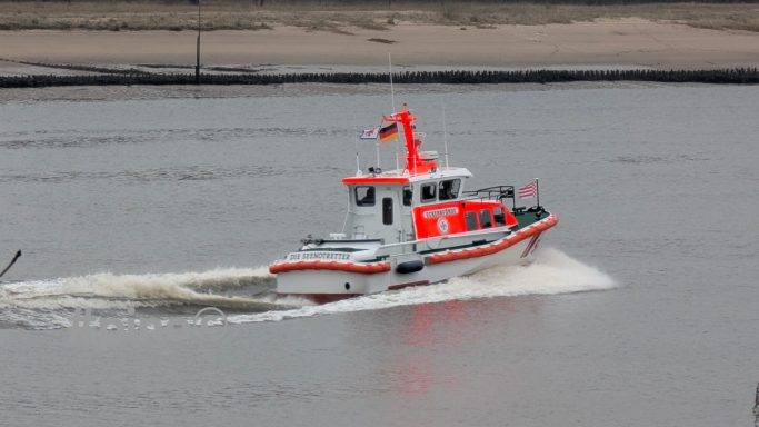 Ein orange-weißes Rettungsboot fährt auf ruhigem Wasser.