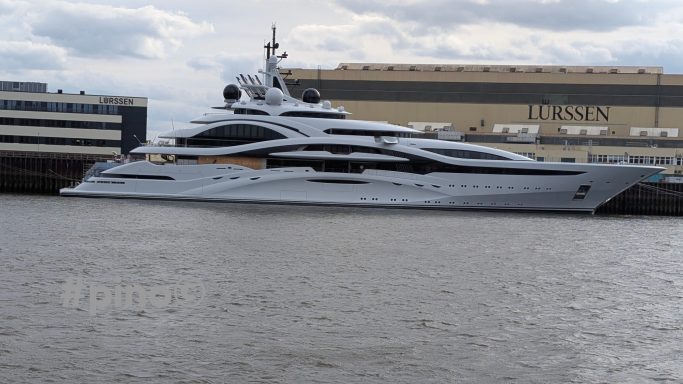 Luxuriöses Yachten-Erscheinungsbild am Wasser, mit hohen Gebäuden im Hintergrund.