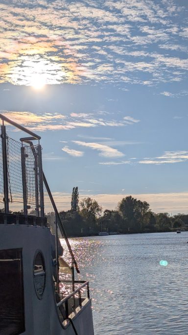 Ein Schiff fährt auf einem ruhigen Wasserweg unter einem sonnigen Himmel.