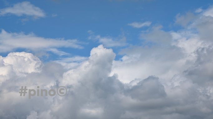Helle Wolken vor blauem Himmel mit einigen Schattenbereichen.