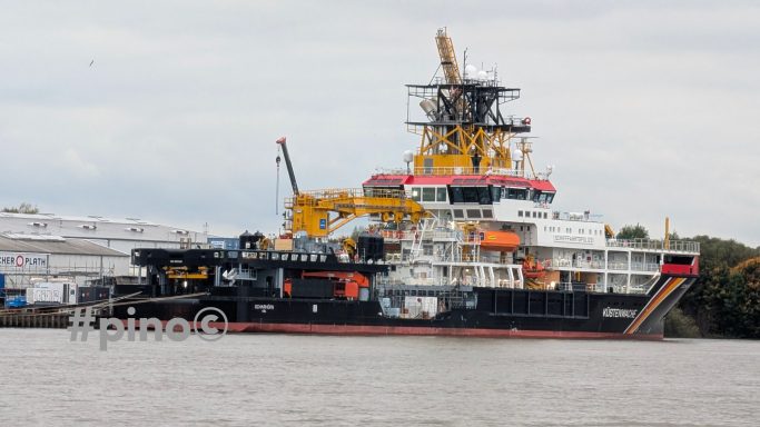 Ein großes Schiff mit gelben Kräne, das im Wasser liegt.
