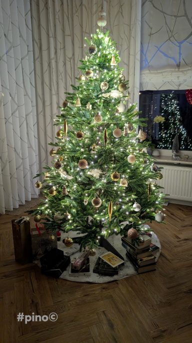 Weihnachtsbaum mit buntem Schmuck und Geschenken unter dem Baum.