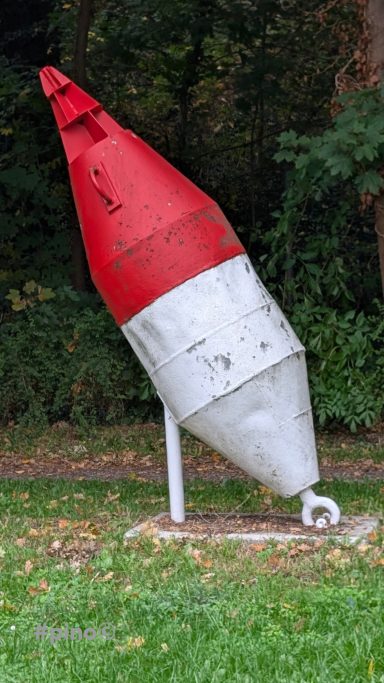 Roter und weißer Bouyenkegel auf grünem Gras, leicht geneigt.