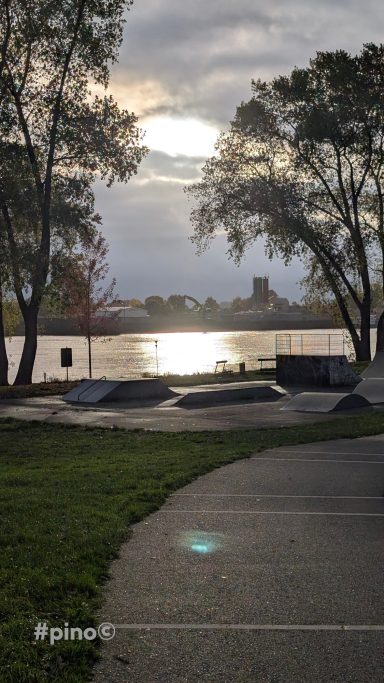 Sonnenreflexionen auf dem Wasser, umgeben von Bäumen und einer ruhigen Landschaft.