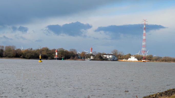 Ruhiger Fluss mit mehreren Boote und einem Sendemast im Hintergrund.