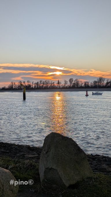 Sonnenuntergang über Wasser, reflektiert auf der Oberfläche, mit Silhouetten von Bäumen.