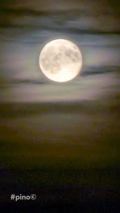 Helle Vollmondscheibe hinter wolkigem Himmel.