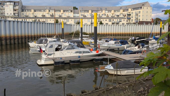 Hafen mit mehreren Booten und einem Wohngebäude im Hintergrund.