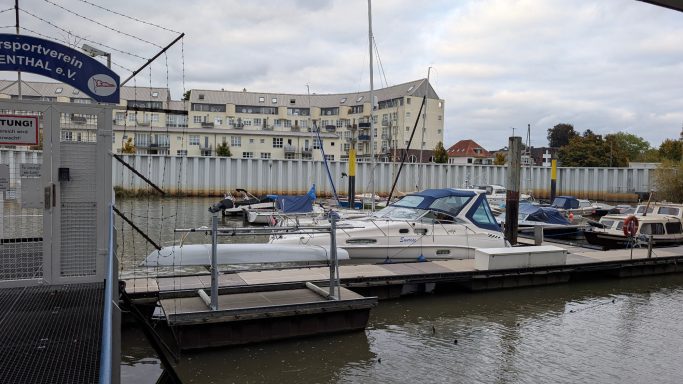 Yachthafen mit mehreren Booten und einem modernen Gebäude im Hintergrund.