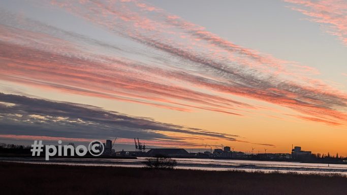 Abendhimmel mit bunten Wolken über einer Stadt am Wasser.