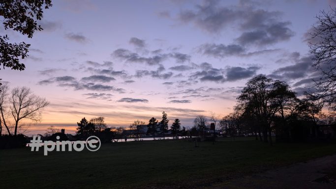 Blick auf einen Abendhimmel mit farbigen Wolken über einer ruhigen Landschaft.