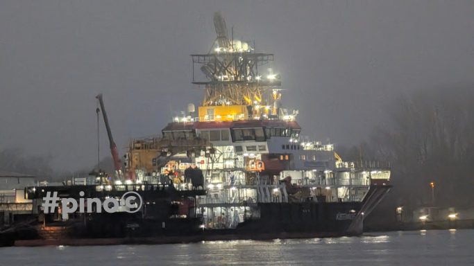 Ein Schiff mit Licht installiert, im Nebel, am Wasser.