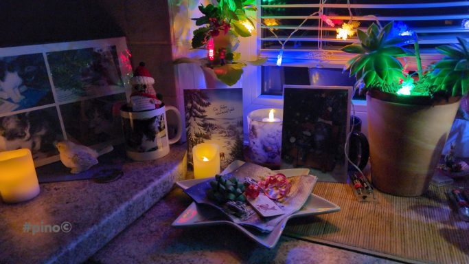 Ein festlich dekorierter Tisch mit Kerzen, Pflanzen und bunten Lichtern.