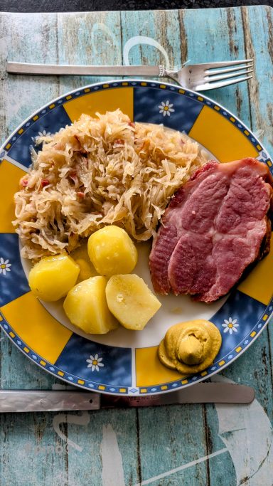 Teller mit Sauerkraut, Kartoffeln, gepökeltem Fleisch und Senf.