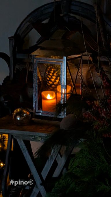 Brennende Kerze in einem dekorativen Laternen-Rahmen auf einem Tisch.