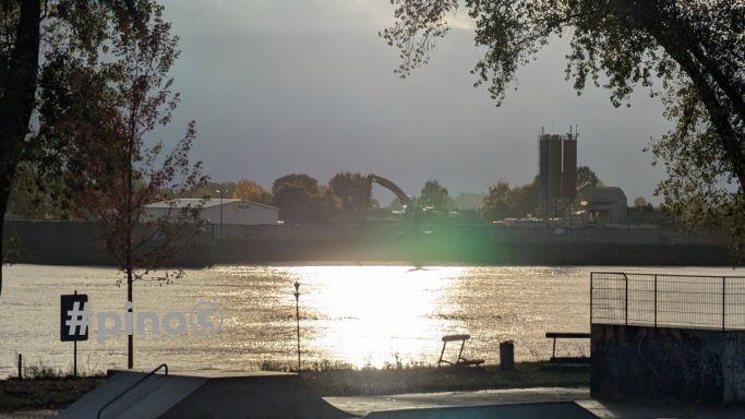 Silhouette einer Stadtlandschaft bei Sonnenuntergang mit spiegelndem Wasser.